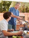 Senior dad serving his wife food at a family barbecue