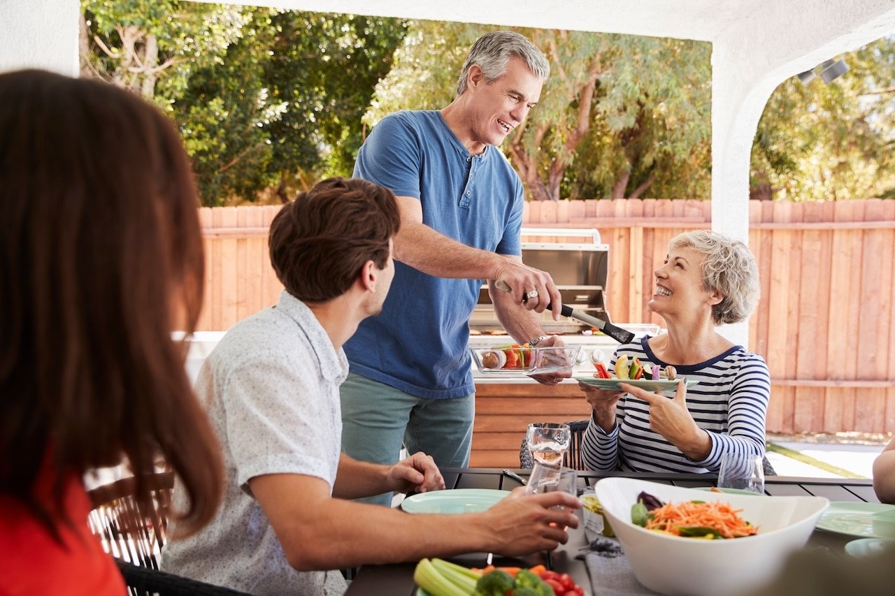 Senior dad serving his wife food at a family barbecue