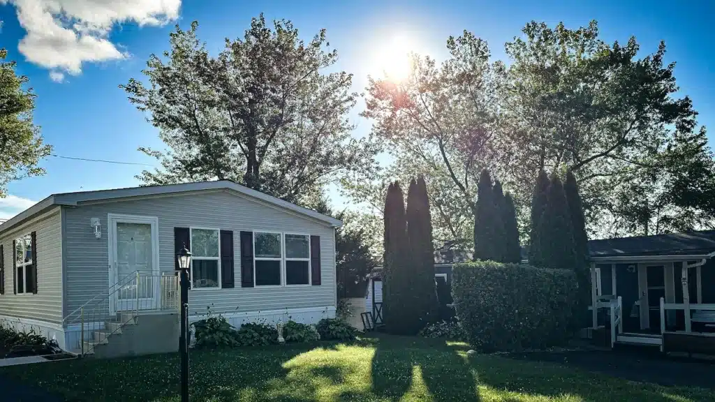 Manufactured home with front porch and landscaping in afternoon sun at a Valley Community Management property