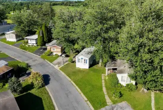 Aerial view of a tree-lined manufactured home street in Pennsylvania with green lawns and single-wide units