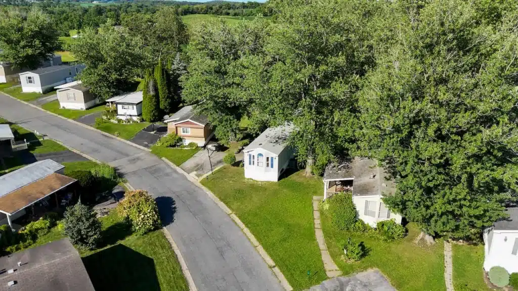 Aerial view of a tree-lined manufactured home street in Pennsylvania with green lawns and single-wide units